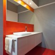 Bagno opsiti. Intersezione tra parete arancio/rossa e parete grigia e pavimento.